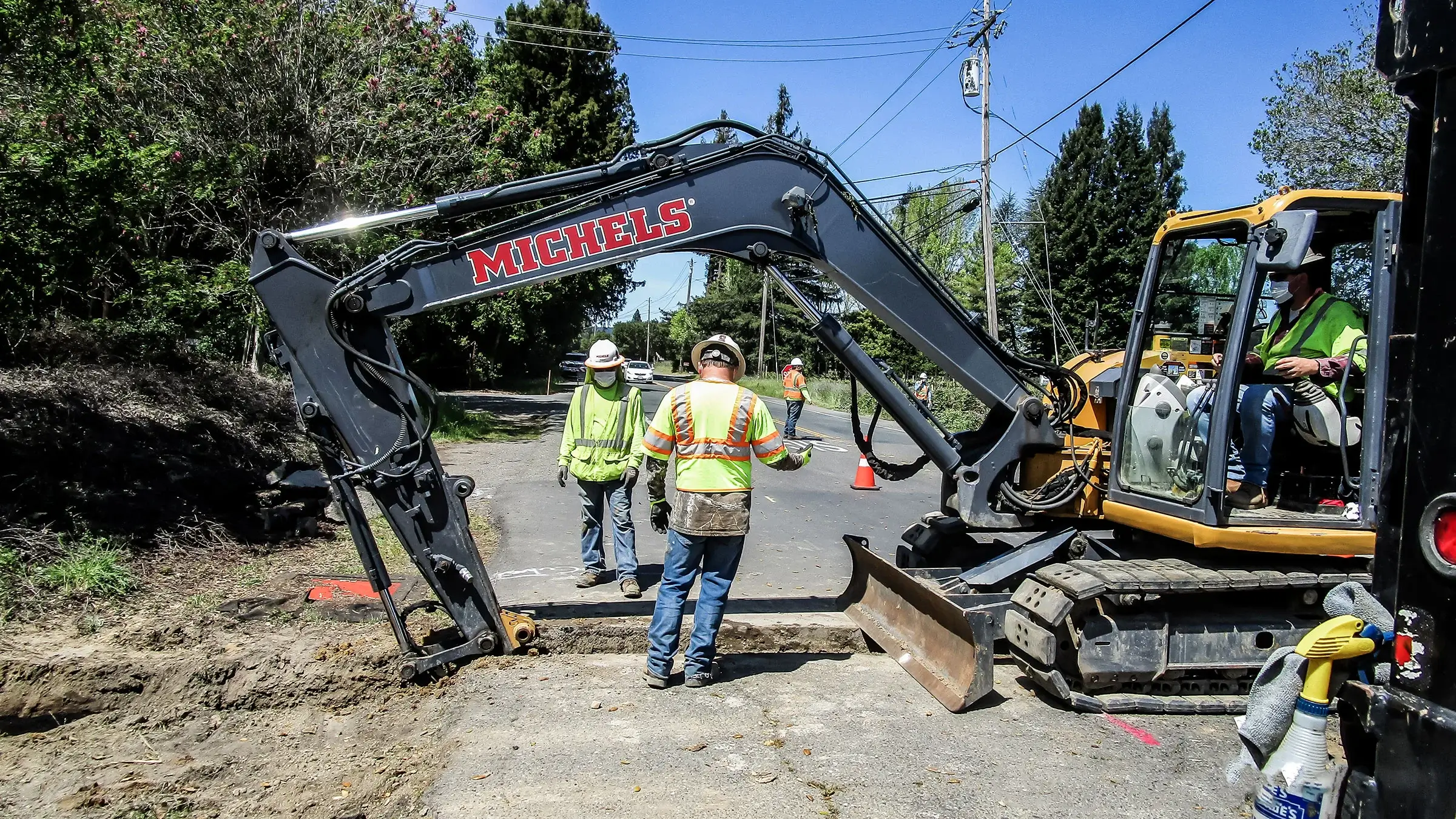 Michels crew members inspect a small trench in the side of a road.