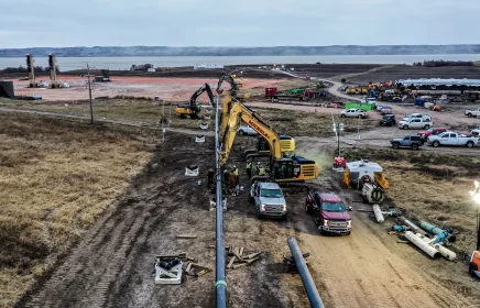 A long pipeline is assisted into the ground and beneath a river through assistance of heavy equipment.