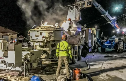 Two crew members prepare protective coating solution to spray in underground sewer tunnel