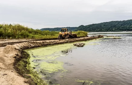 Dozer levels shoreline next to lake after repairing the shoreline due to erosion