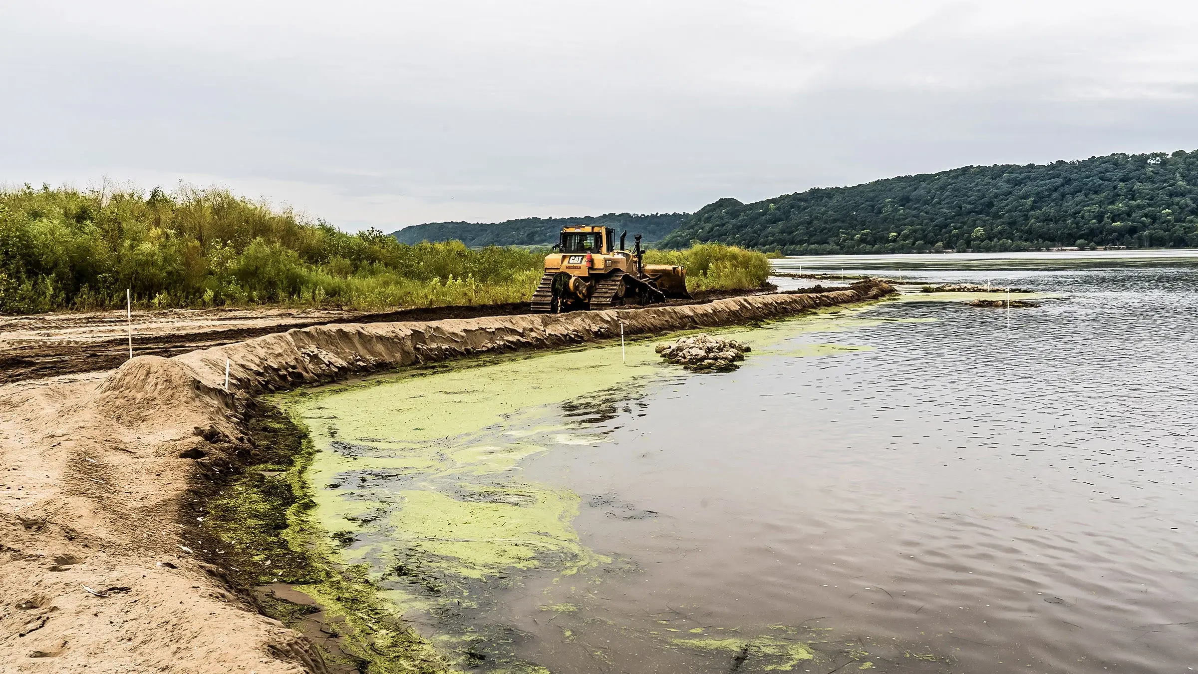 Dozer levels shoreline next to lake after repairing the shoreline due to erosion