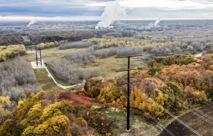 Main power line featured against a hillside with leaves changing colors for fall