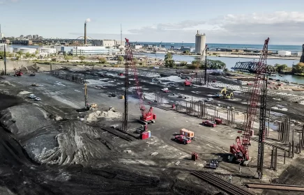 A drill rig and several cranes operate on a foundations jobsite near Milwaukee