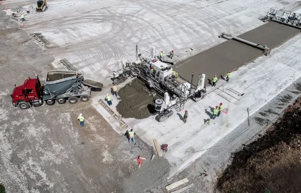 Paving machines lay concrete at an airport