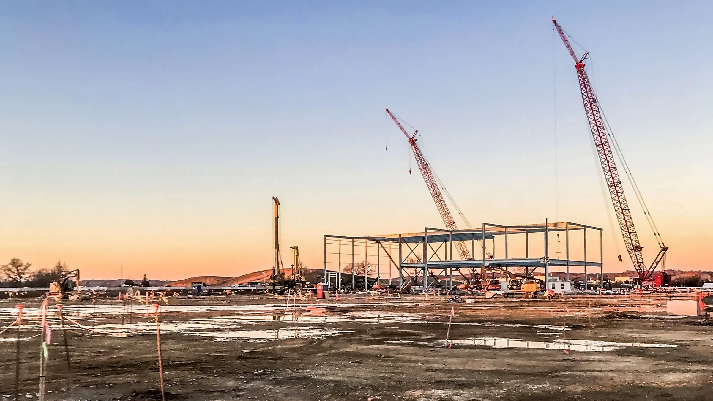 Two cranes working on a project at sunset.