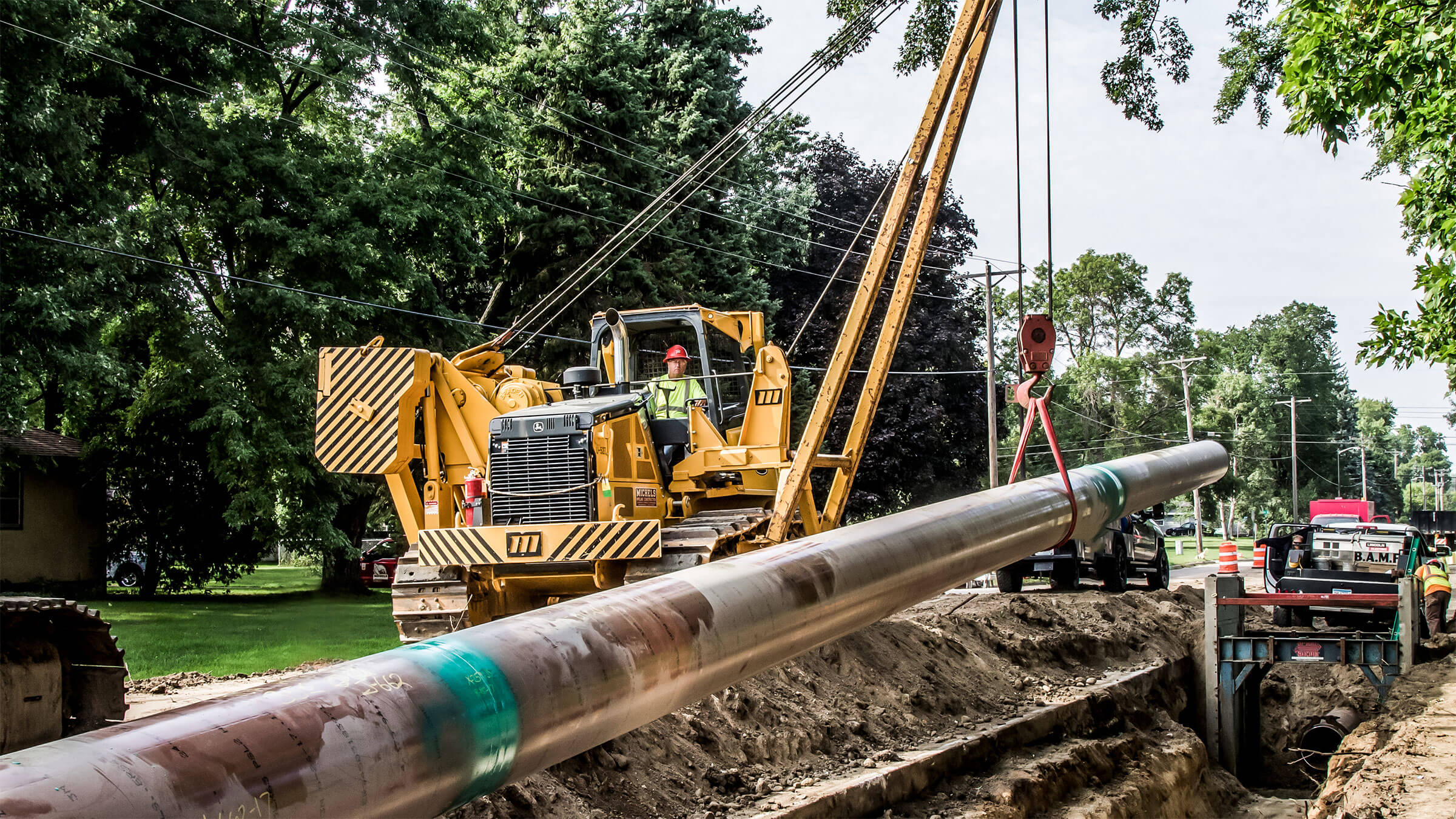 A pipelayer operater lowers a pipeline into a trench.