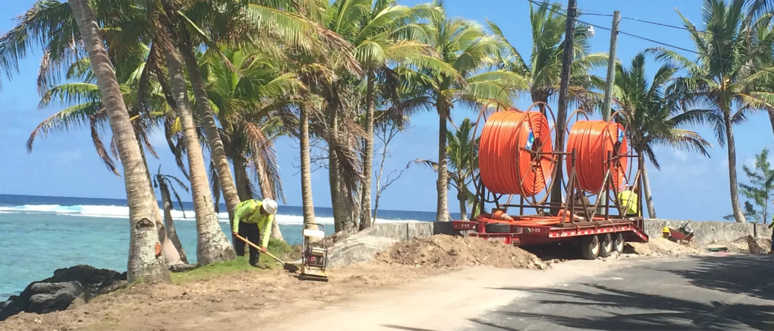 A Morgan Luis crew member working near the ocean and palm trees in Guam