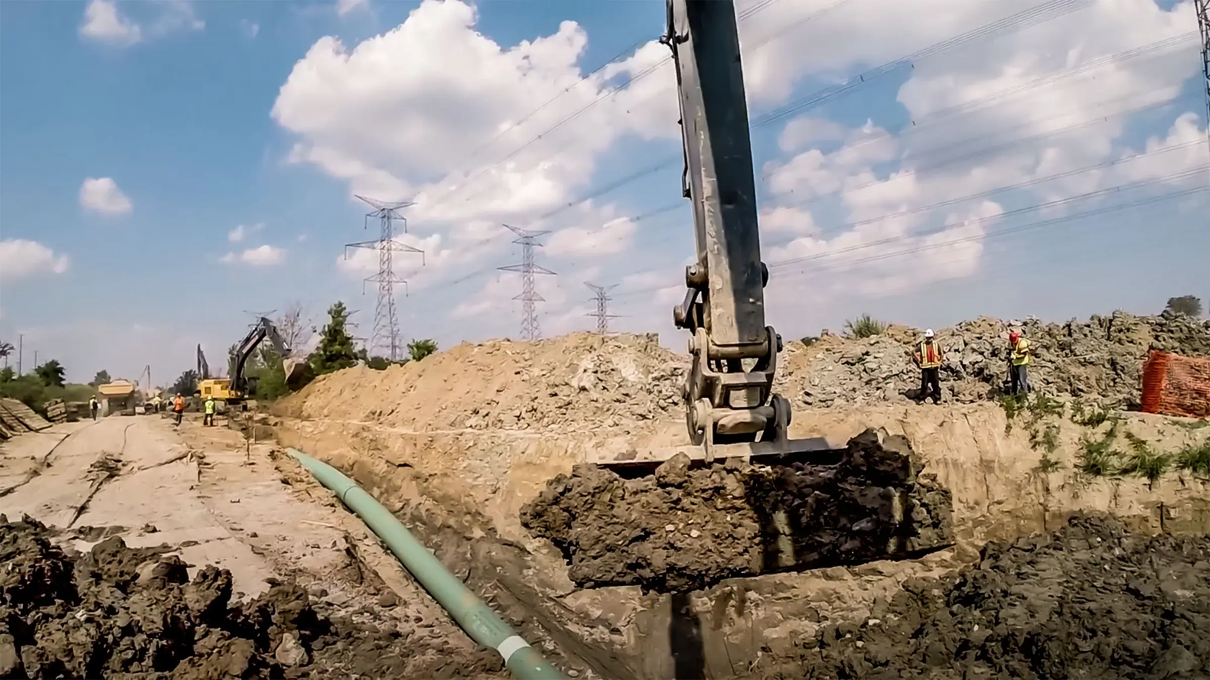 Excavator bucket filled with dirt on a partly cloudy day.