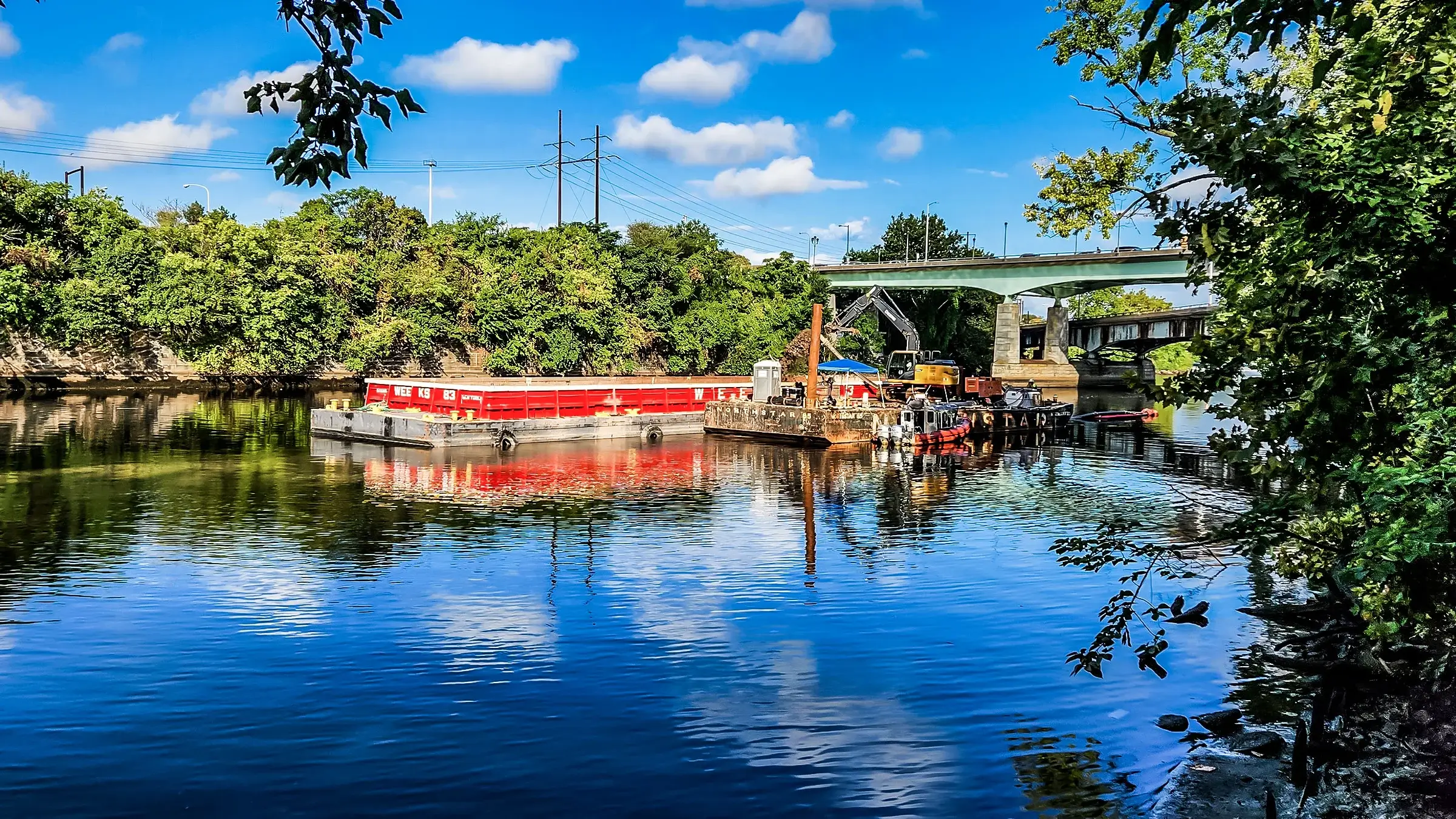 A excavator operates on a barge on a river