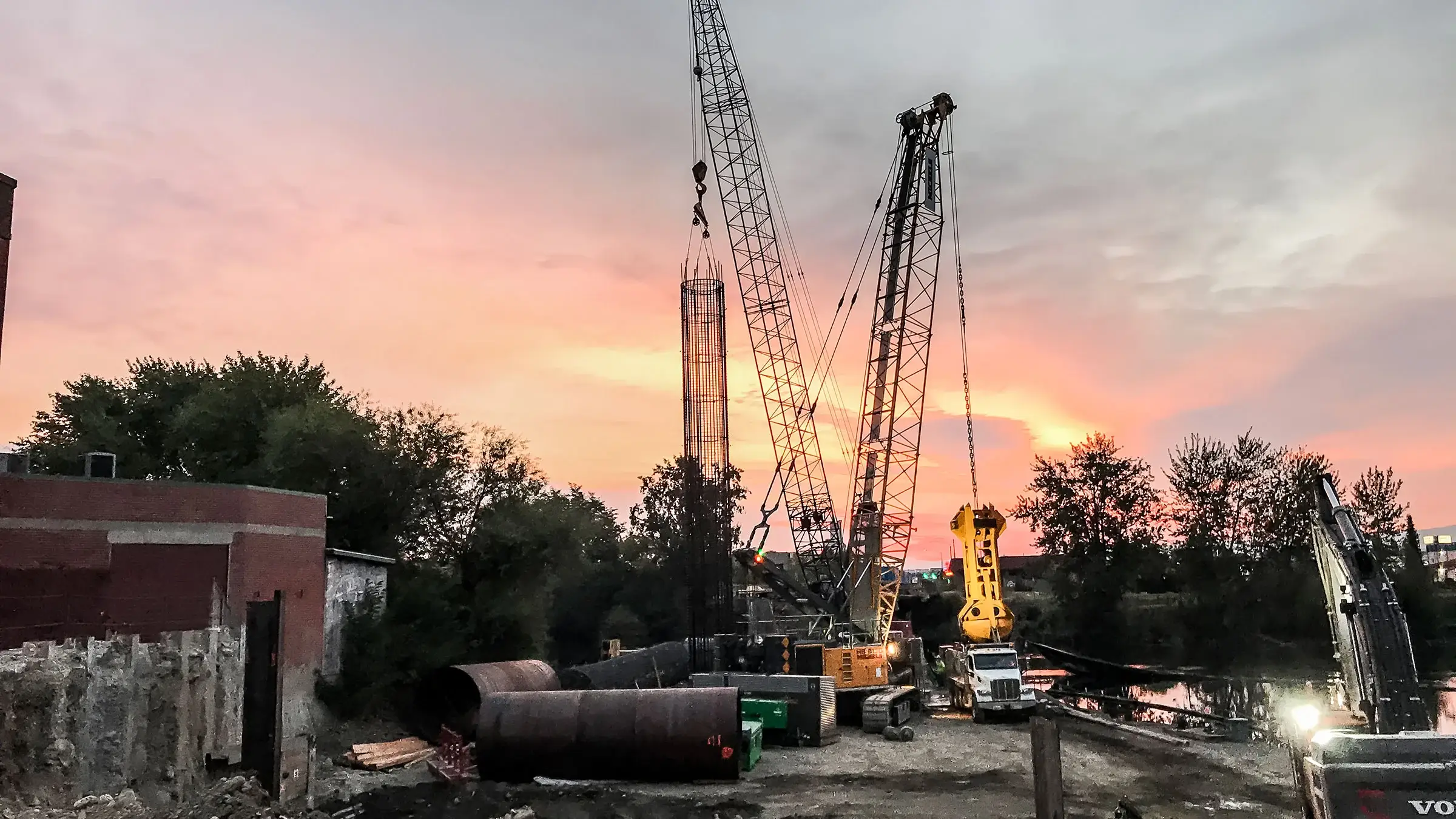 Cranes extended in the air overlooking the sunset.