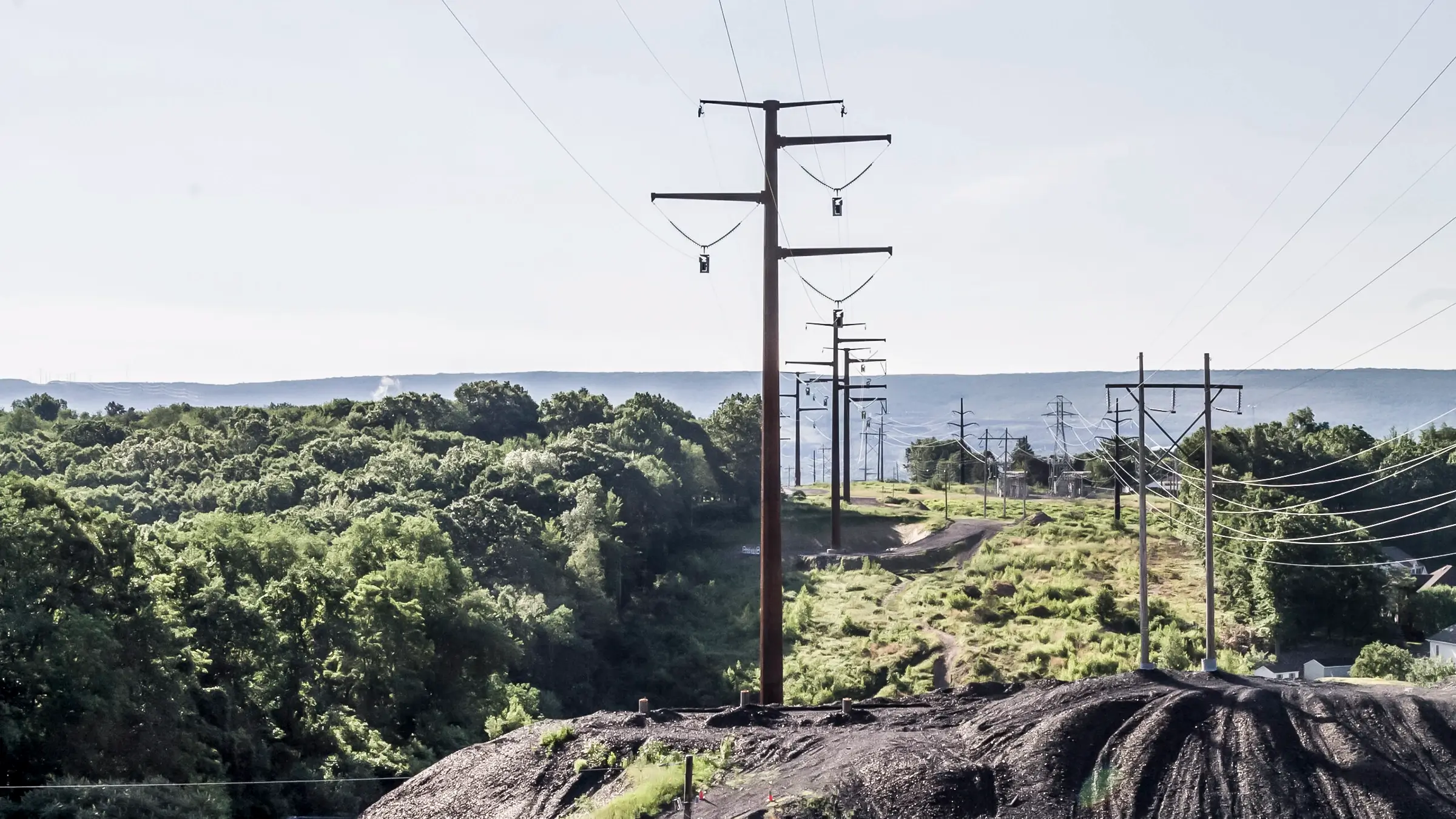 A power line is prepared to get pulled into place in a hilly area