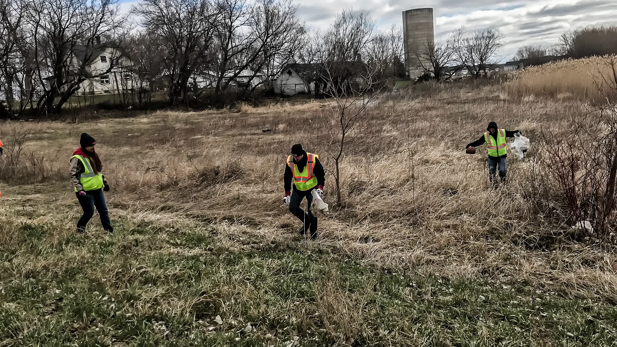 Three men in safety vests cleaning up on earth day