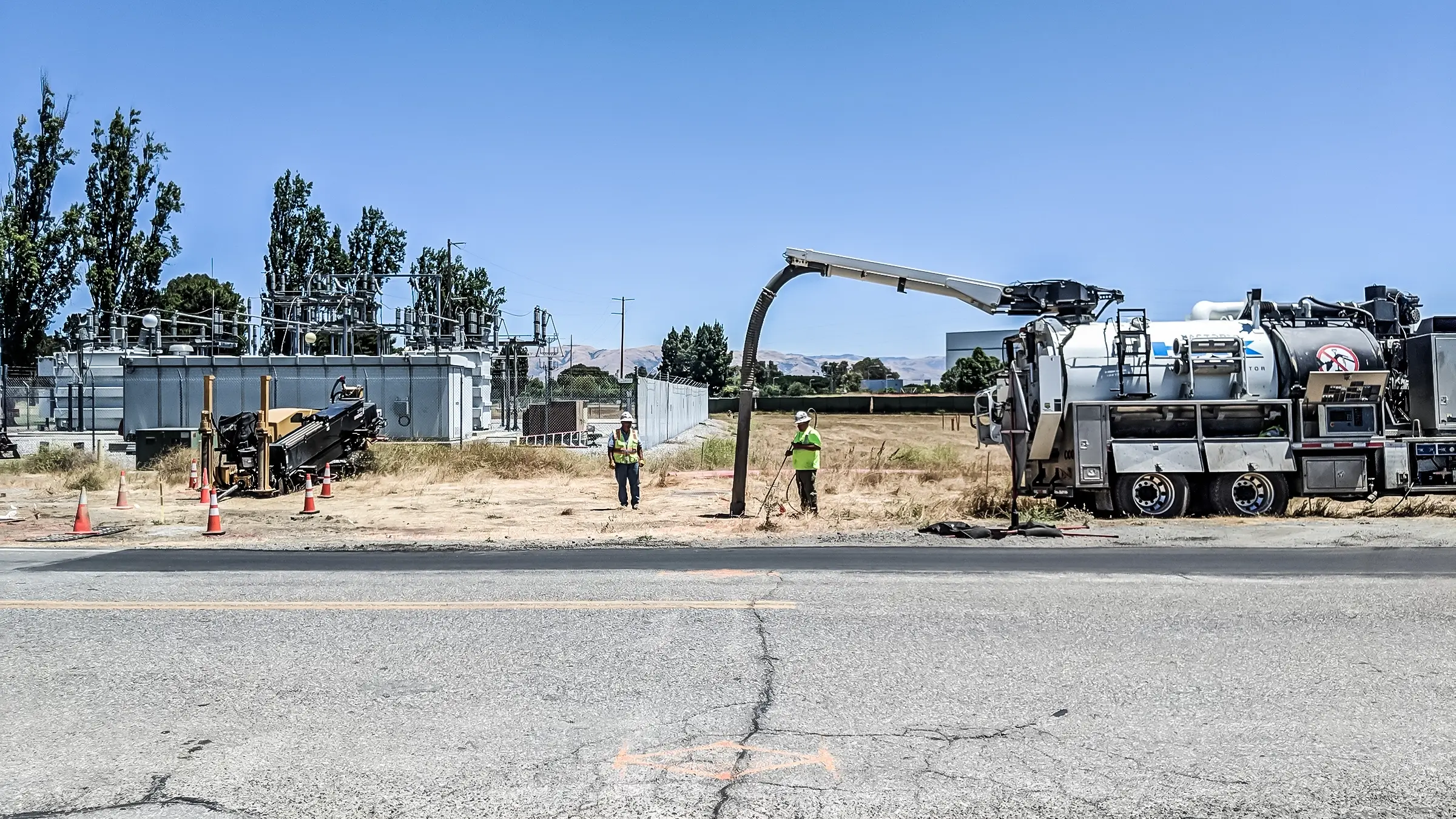 Several crew members and a truck stand near a road.