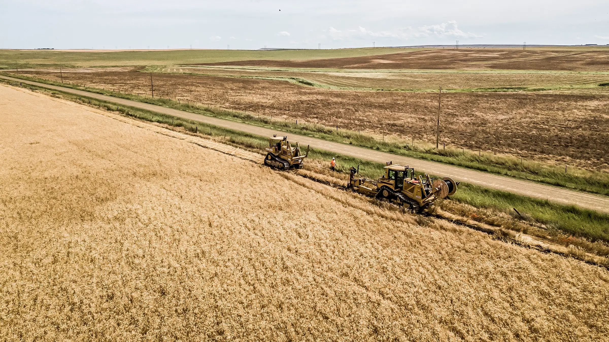Underground cable is installed in a rural Montana field near a road.