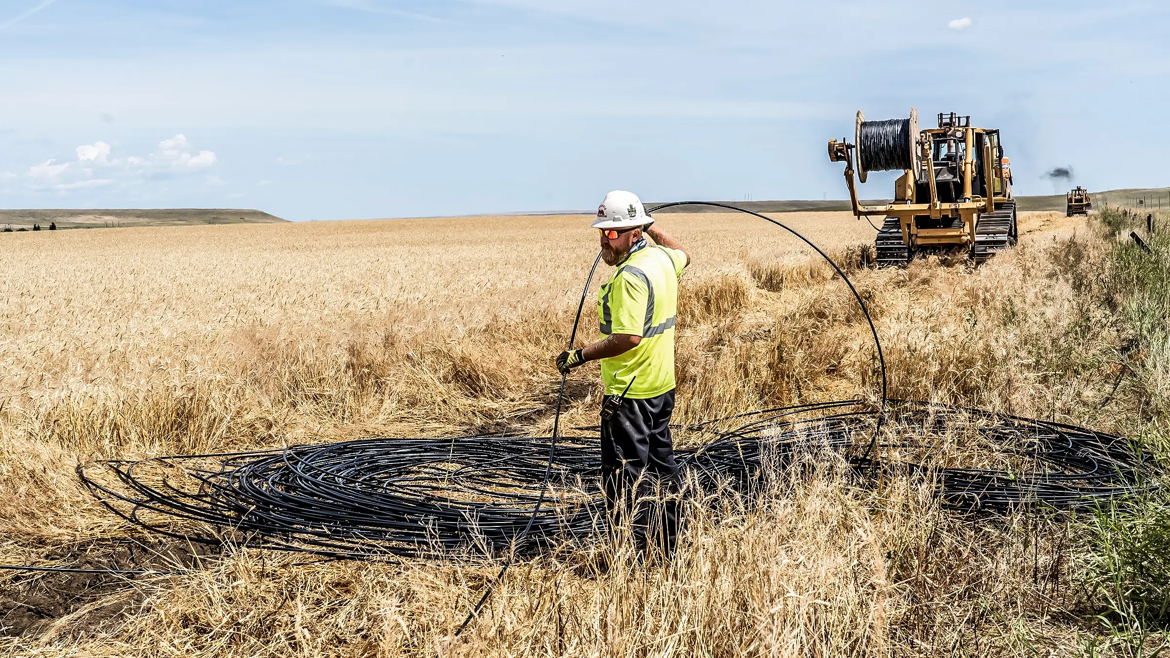 A crew worker handles a large coil of cable.