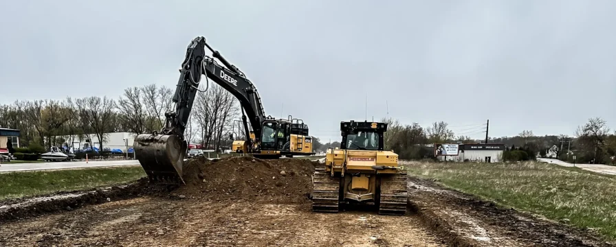 A bulldozer and backhoe layout an excavated road.