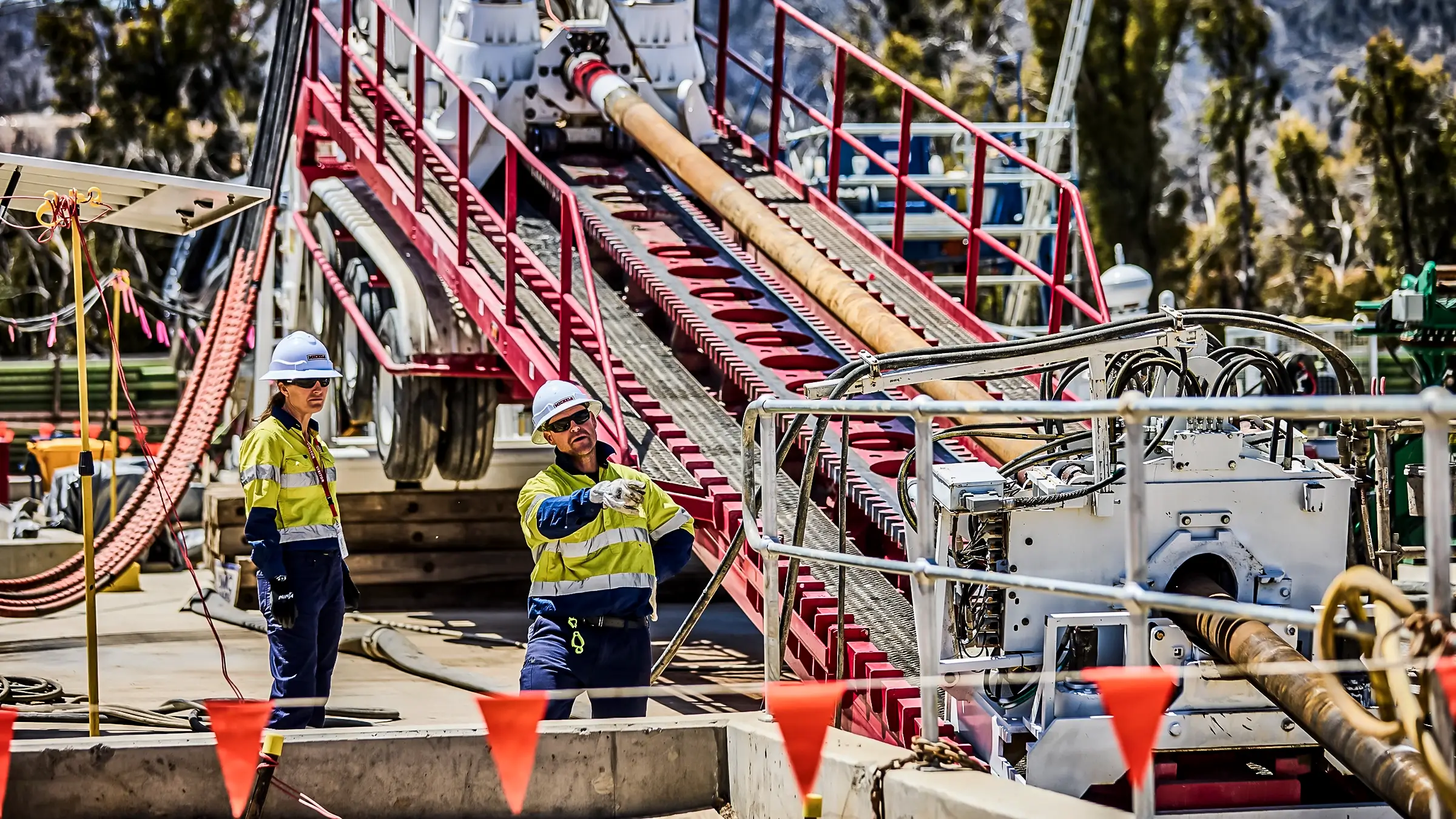 Two people standing near an HDD rig.