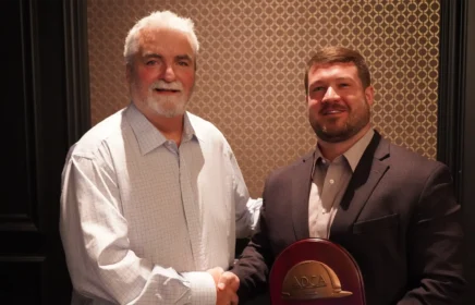 Man shakes hand with Tim Schmitt as he holds his award.