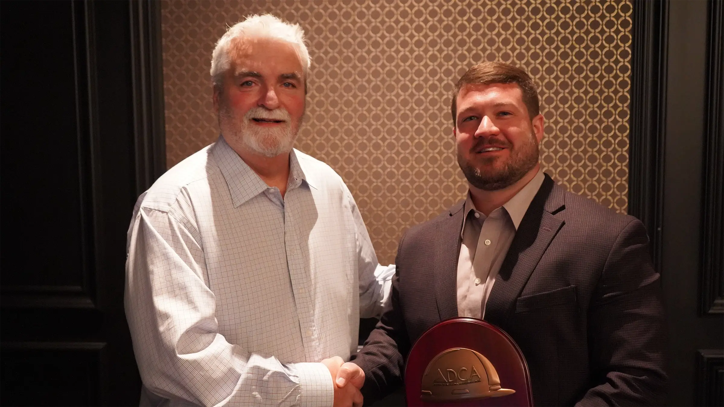 Man shakes hand with Tim Schmitt as he holds his award.