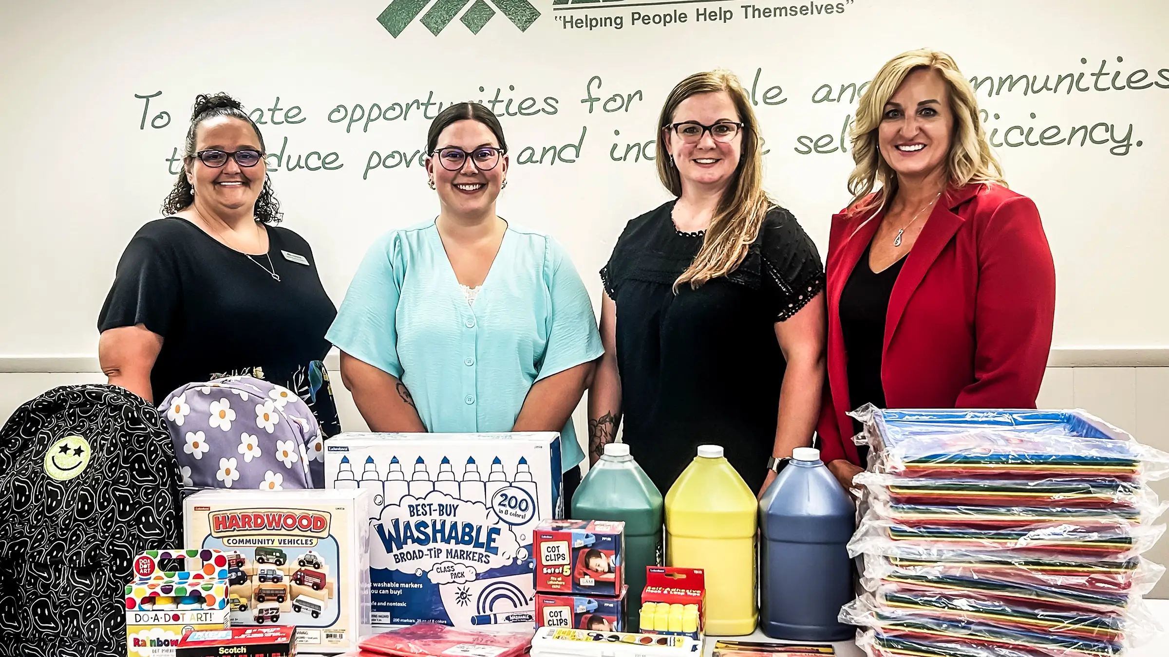 Four women standing around donated school supplies.