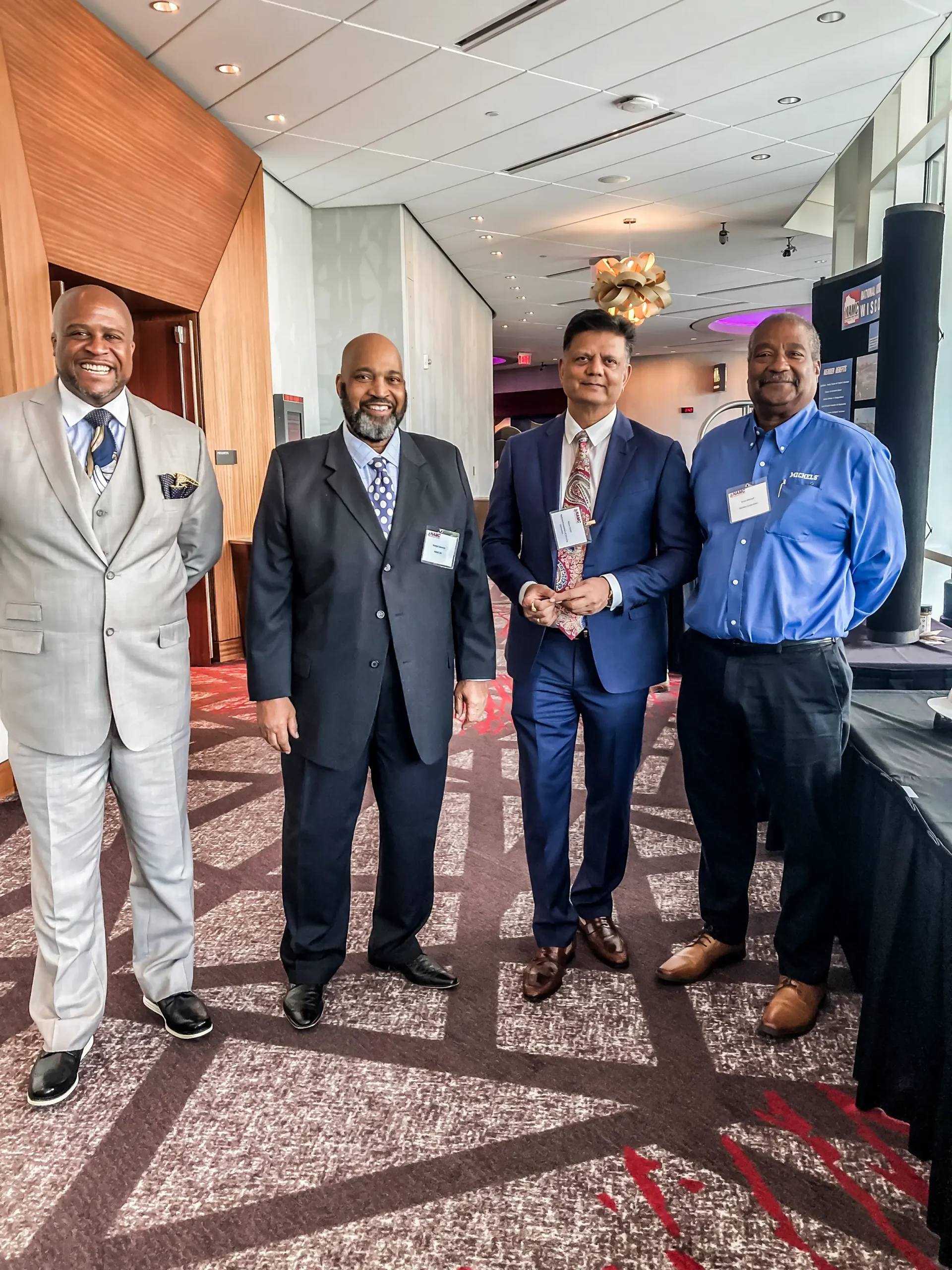 Four men in suits stand in a group at a Supplier Diversity event.
