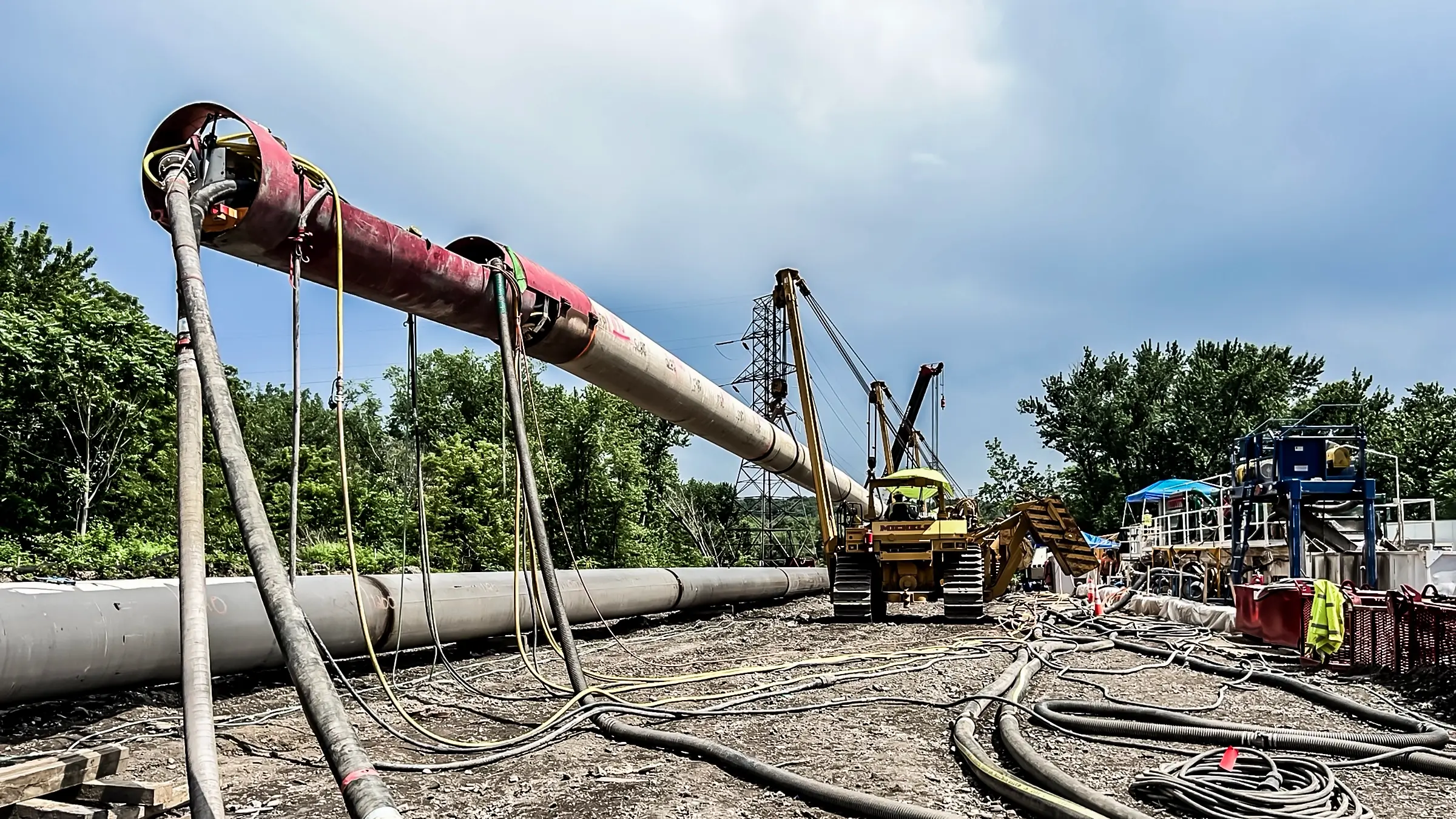 Portions of large diameter pipeline held up by pipelayers.