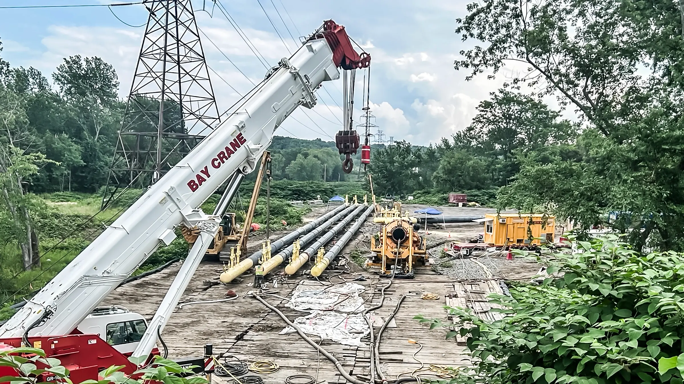 A small crane with a Direct Pipe thruster inn the background amongst portions of pipe to be installed.