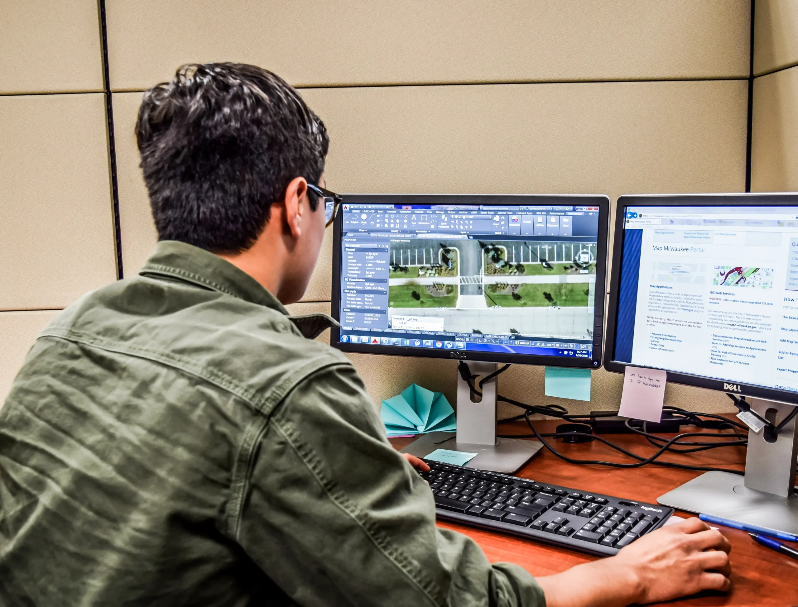 Man at desk facing away at two monitors.