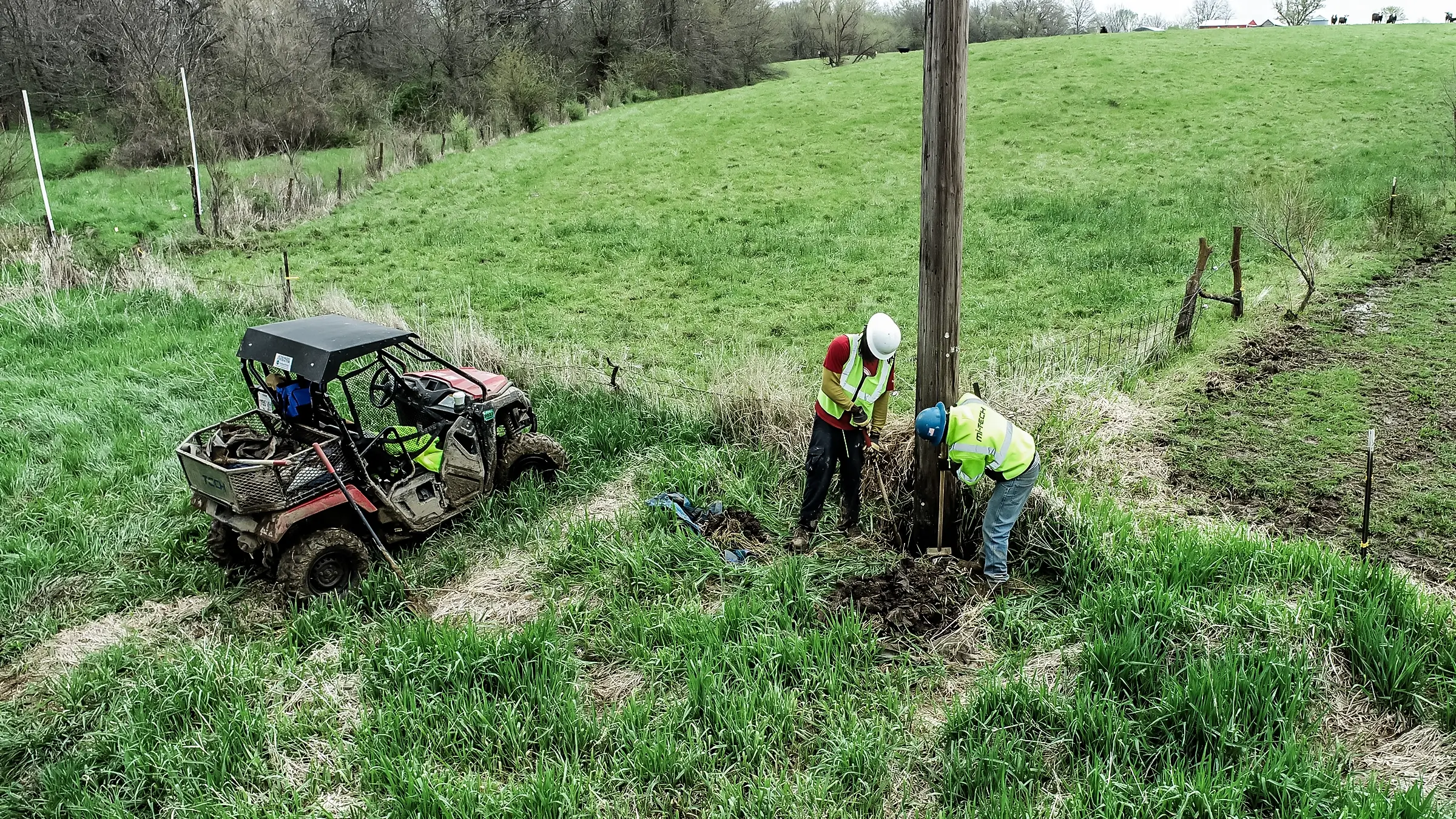 Several crew members inspect a telecommunications pole.